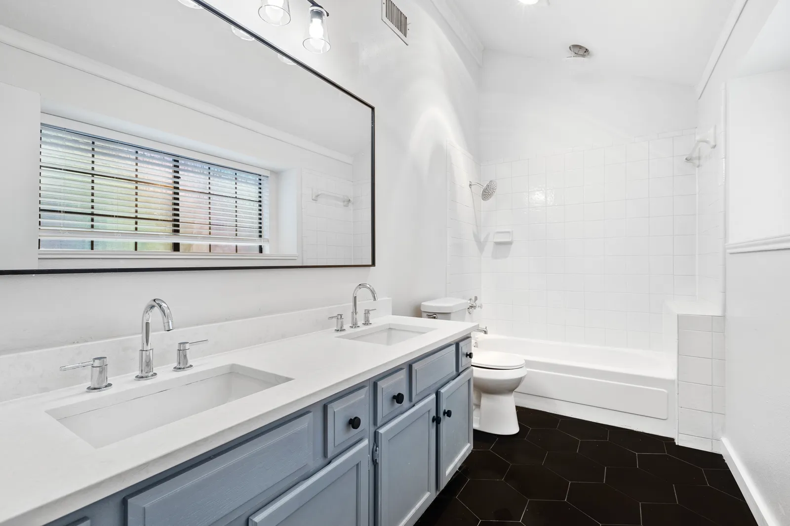 Hall bathroom at Haven Pl in Allen, TX after the pre-sale refresh: painted vanity, new mirror, lighting, and tile