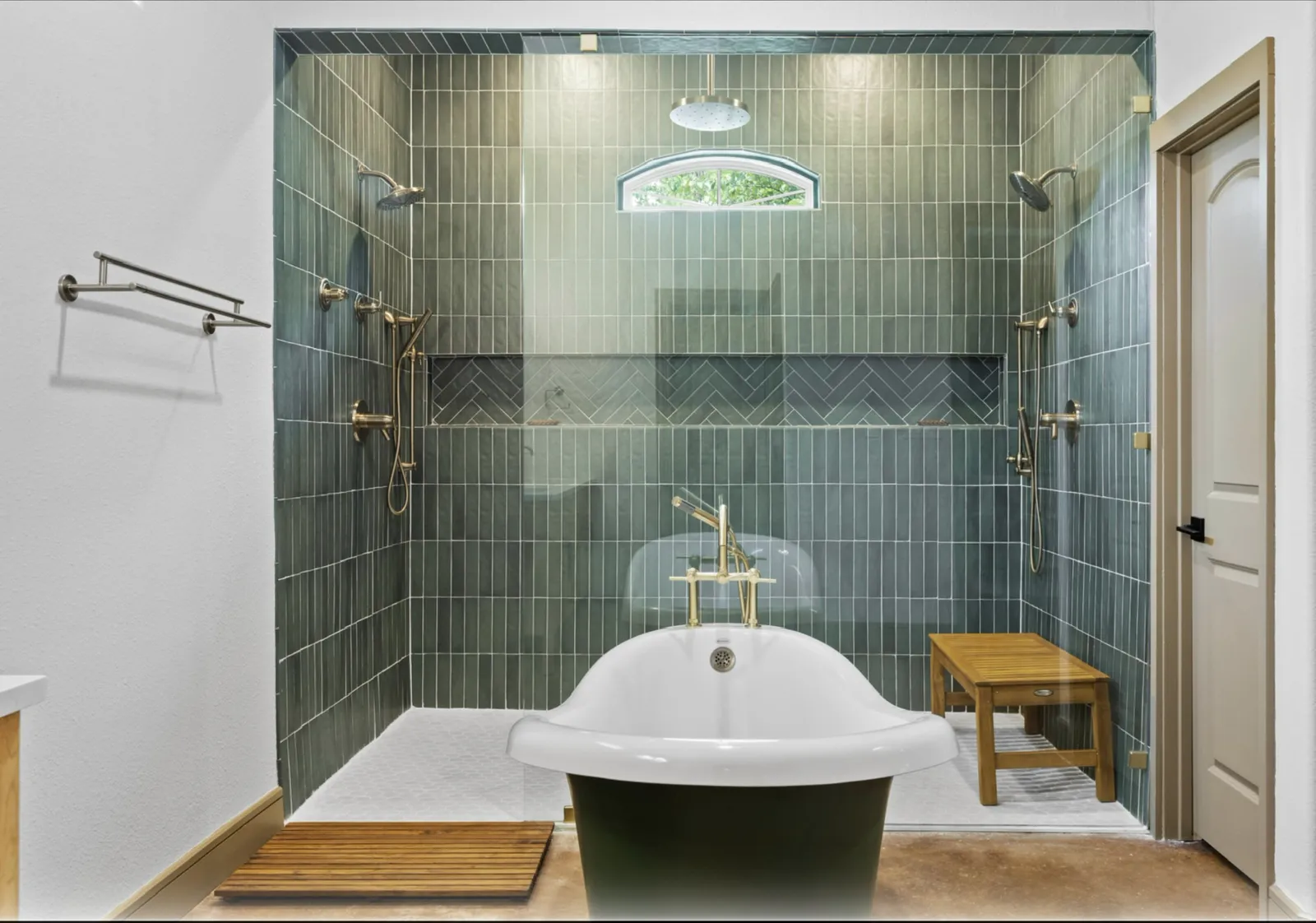 New primary bathroom at Lake Breeze Dr. in McKinney: green vertical tile, dual rain showers, the reused clawfoot tub, and a teak bench
