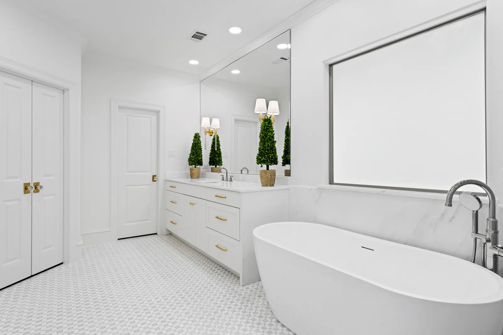 Primary bathroom at Revere Pl. in Lakewood: white double vanity with brass hardware, freestanding tub, and gray subway-tile shower