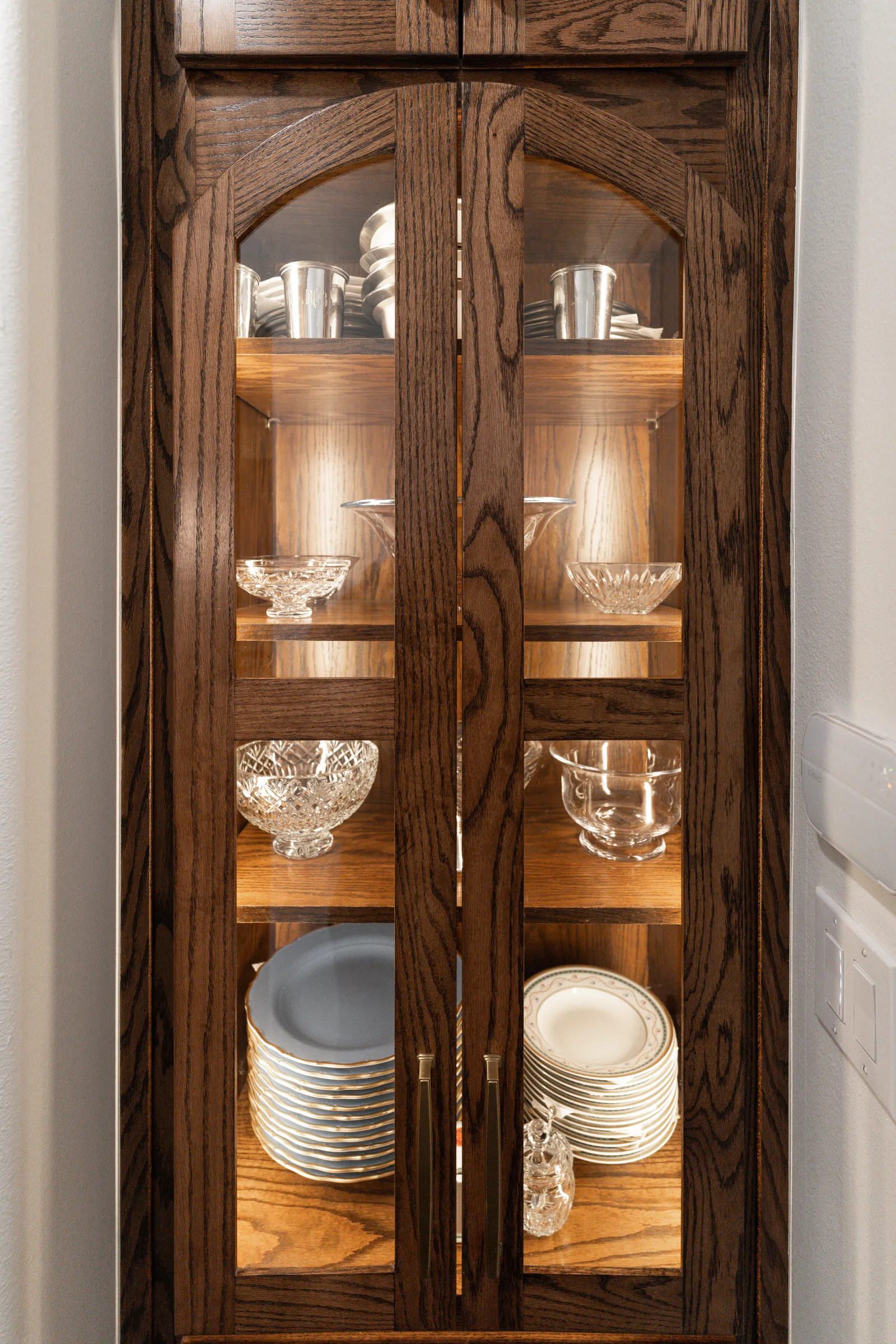 Refinished oak china cabinet with lit glass shelves at Revere Pl. in Lakewood