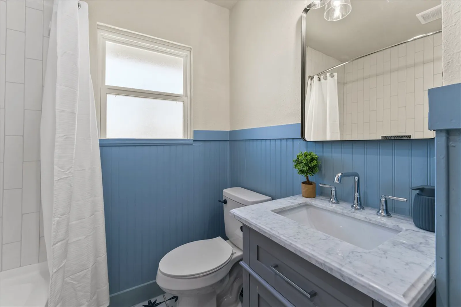 Guest bath with blue beadboard, patterned tile floor, and a new vanity at Sherman St. in McKinney