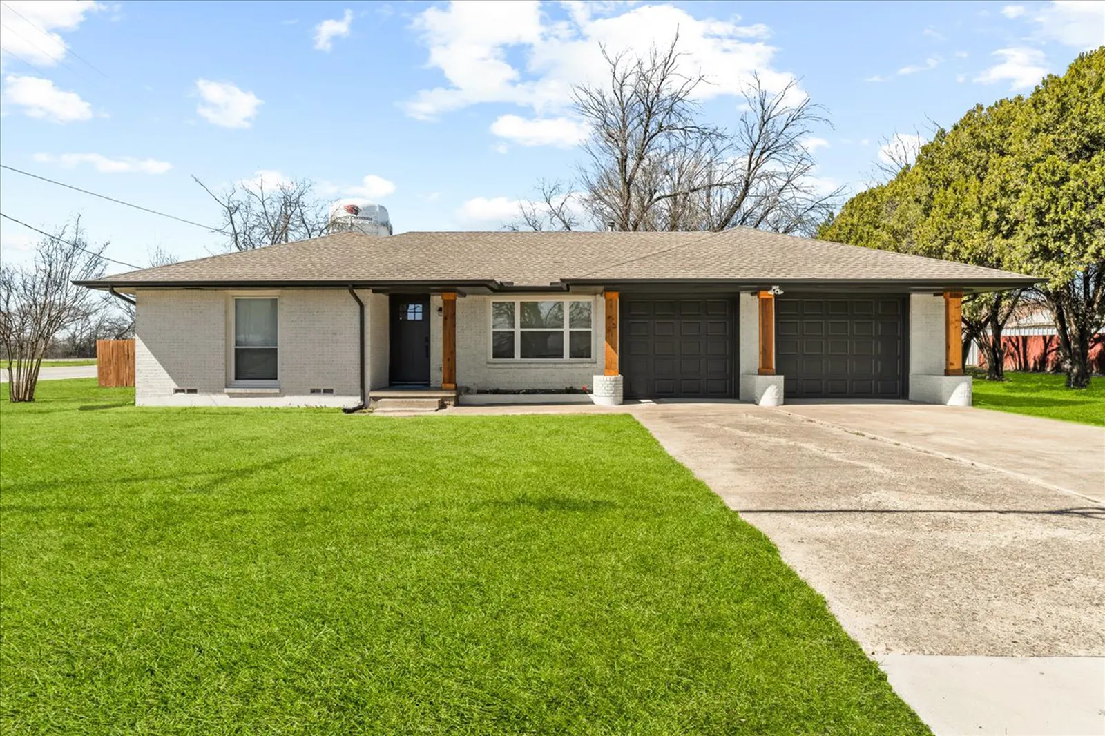Sherman St. in McKinney after the renovation: painted brick ranch with a fresh lawn and a new front door