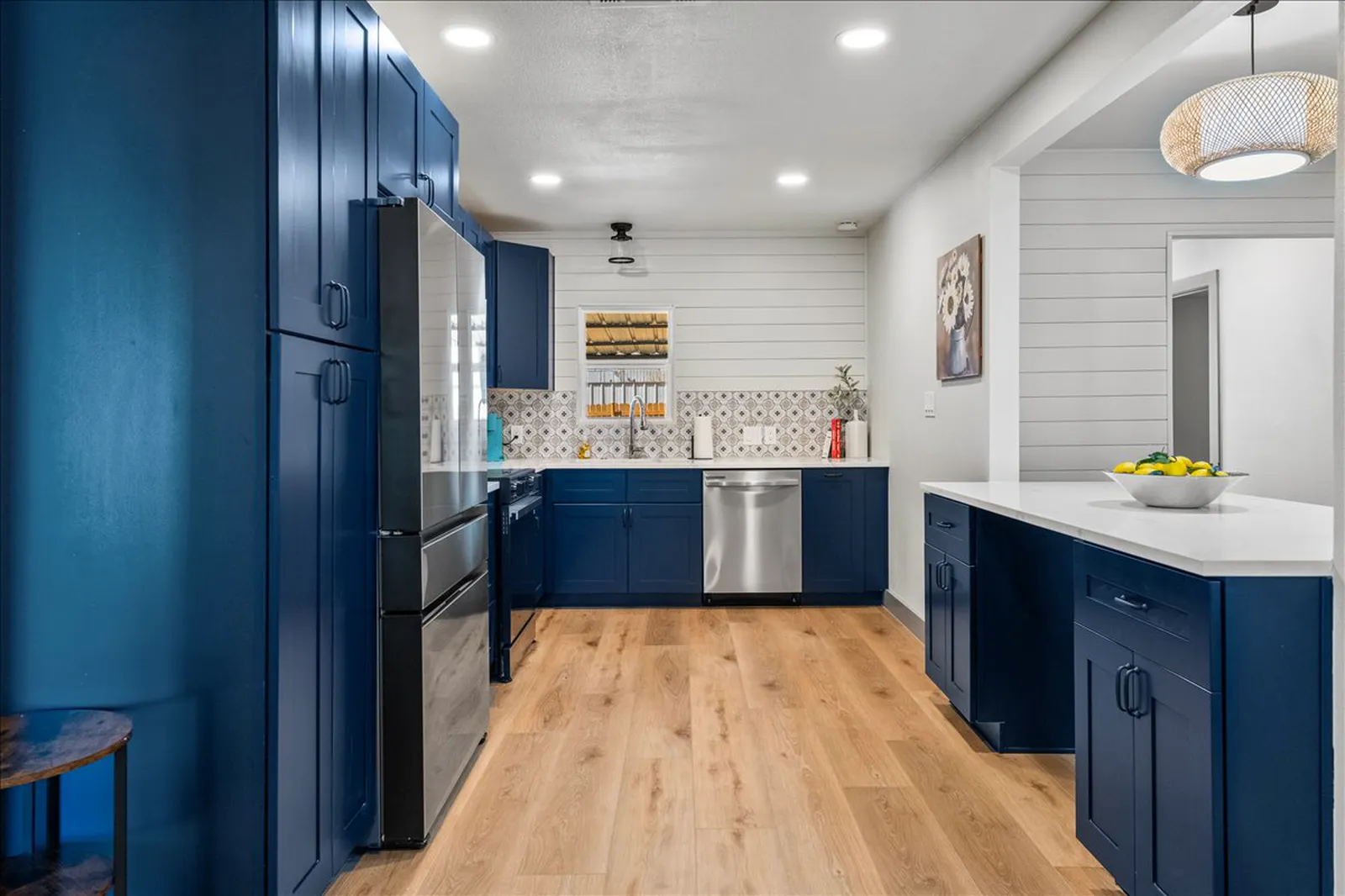 Navy kitchen with white quartz counters, patterned tile backsplash, white shiplap, and white oak floors at Sherman St. in McKinney