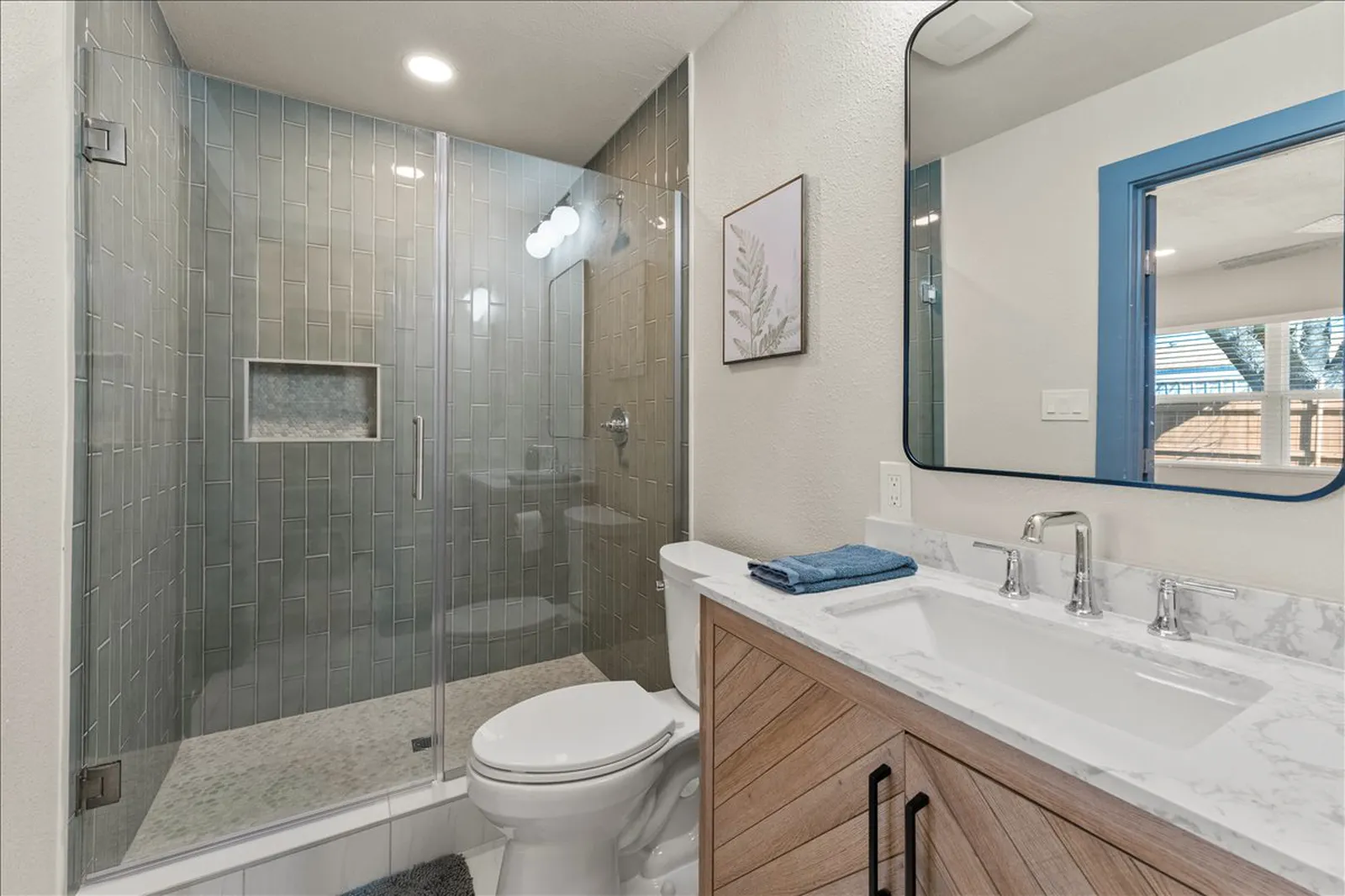 Primary bath with a tile shower and wood vanity at Sherman St. in McKinney
