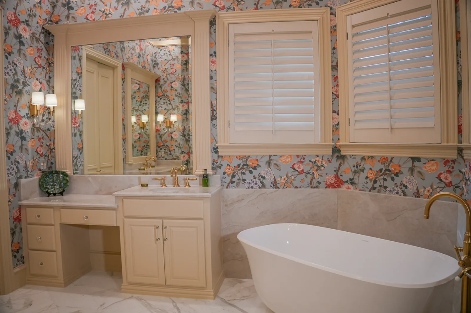 Primary bathroom at Shubert Ct. in Dallas: Lee Jofa wallpaper, cream cabinetry, freestanding tub, and Newport Brass fixtures